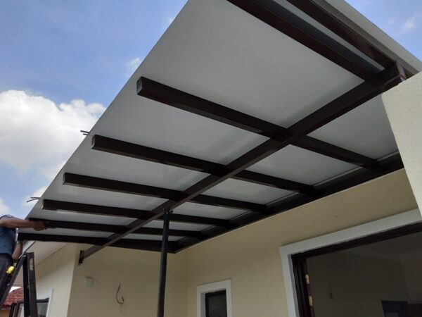 A man is installing an awning roof on a house, working with ACP sheets and panels for a durable finish